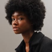 portrait of a black woman named Jessica Randall looking at the camera from her left side and wearing black shirt and only upto her neck is visible